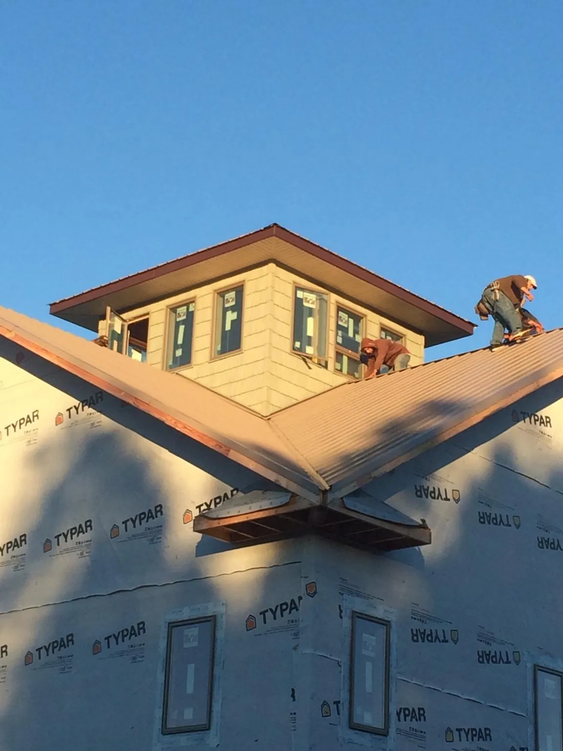 Roofers working around a rooftop cupola on a new metal roof at sunset — Roof Waterproofing in Brewster by Roofing Brothers